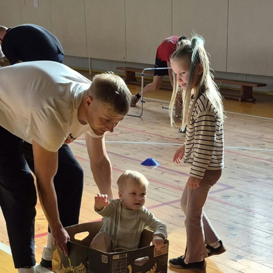Vīrietis stumj kartona kasti ar uzrakstu 